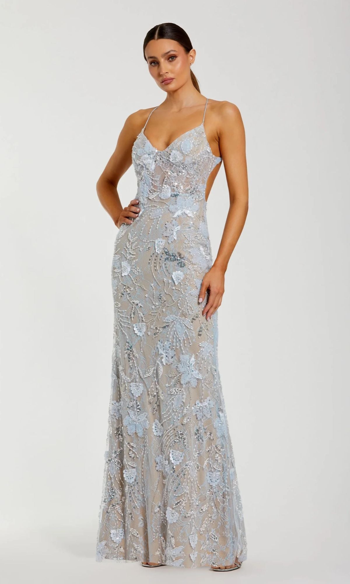 A woman models the Mac Duggal 68892 long formal dress in powder blue, featuring thin straps and a sheer overlay with light blue floral embroidery for an elegant, floor-length style.